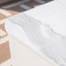 Close-up detail of the realistic white marble veining on the Elementi Annecy porcelain fire table surface.