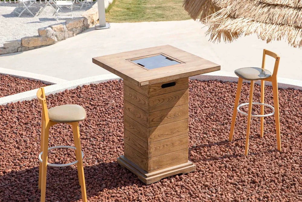 Elementi OFG224 Rova Fire Bar Table 40k BTU used as a cocktail table with drinks on a beachfront patio.