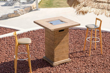 Elementi OFG224 Rova Fire Bar Table 40k BTU used as a cocktail table with drinks on a beachfront patio.