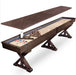 Fully assembled Freetime Fun Rockford Espresso 14' 2-piece shuffleboard table displayed in a luxury home game room next to a stone fireplace on a leopard-print carpet.