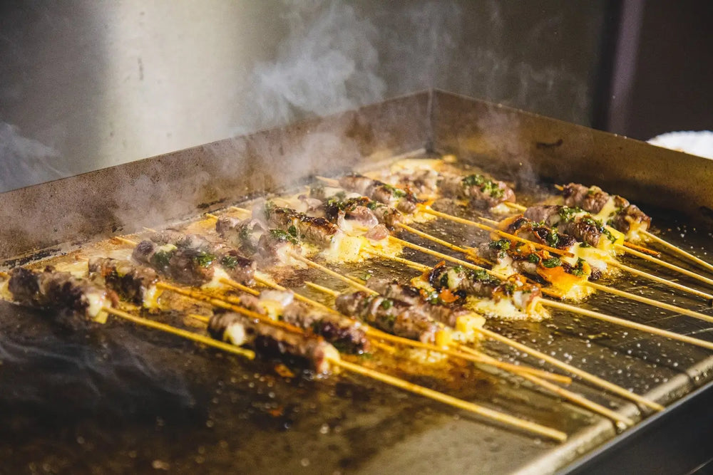 Meat and vegetable skewers sizzling on outdoor stainless steel flat top griddle
