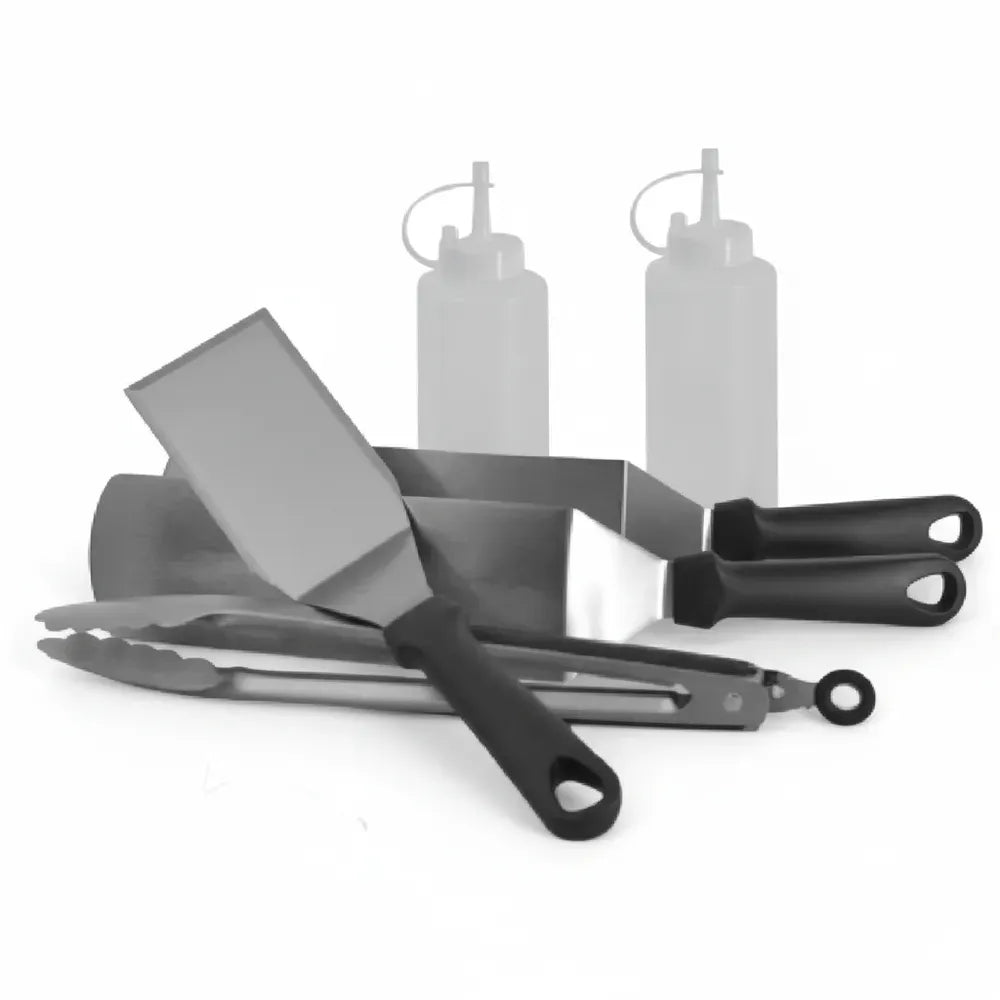 Hand using a heavy-duty stainless steel spatula from the Le Griddle accessory kit on a hot griddle surface.