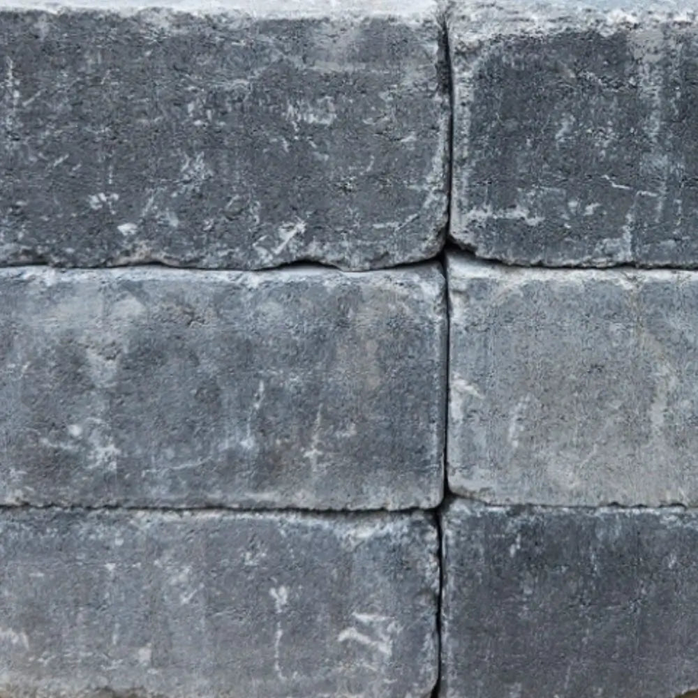 Close-up texture of the Granite color finish for the Travertine TessaRai Gas Fire Pit, featuring charcoal and deep grey stone blocks.
