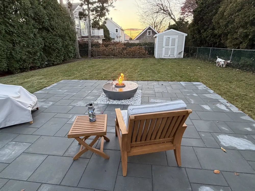 Outdoor living space with a slate patio and a functioning TessaRai 360 fire water bowl as a focal point.