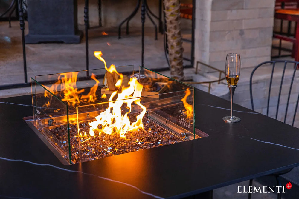 Close-up of the Brugge Bulgaria Black dining table’s linear burner, highlighting the clear glass wind guard and bronze-tinted fire glass reflecting a warm flame.