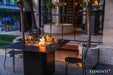 Elementi Plus OFP202BB Brugge Bulgaria Black dining fire table with a dark charcoal porcelain top, styled in a luxury patio setting with white modern chairs.