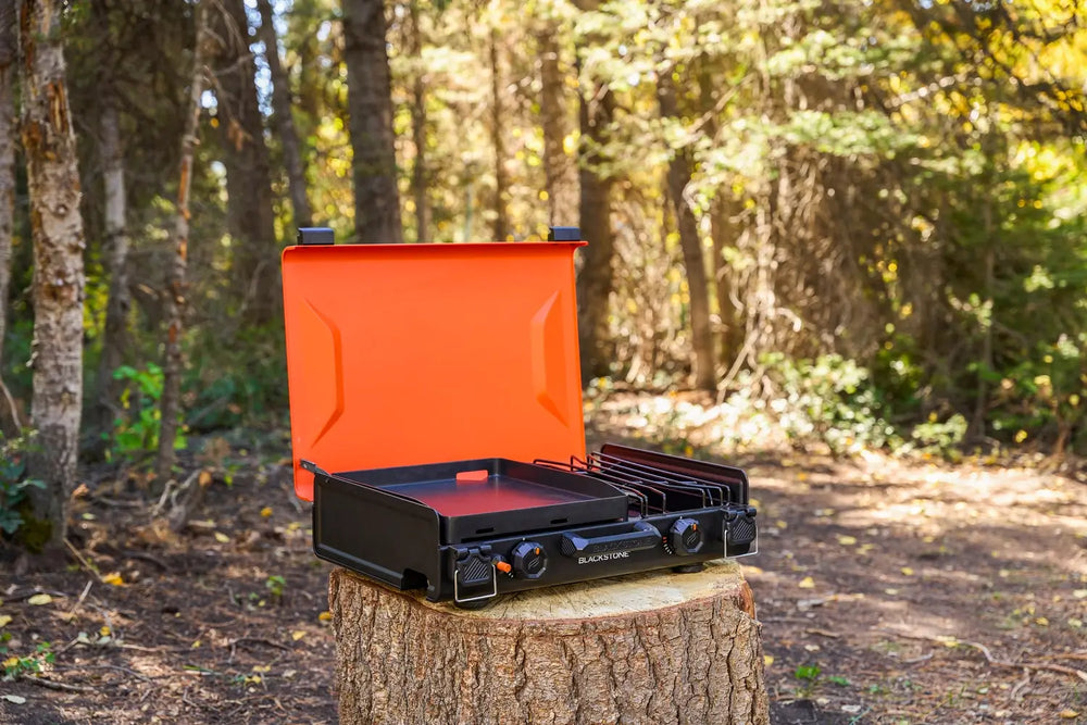Outdoor setup showing black camping griddle with side burner on picnic table