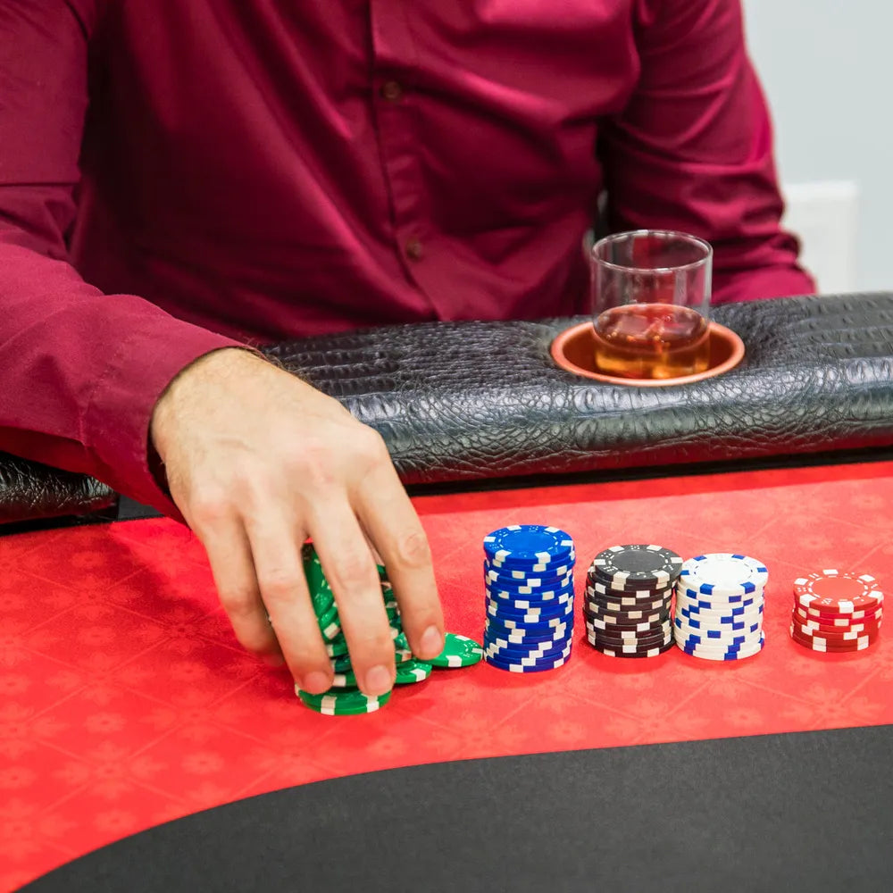Close-up of Triton premium poker table with red felt surface, poker chips, padded black rail, and built-in cup holder for casino-style home games.