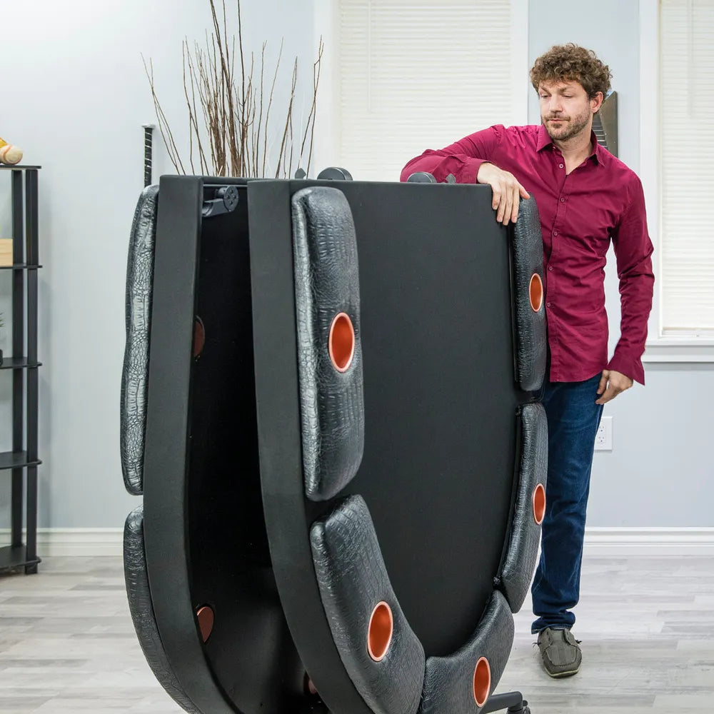 Folded Triton 90-inch poker table standing upright for storage, showing portable space-saving design with padded armrests and built-in cup holders.