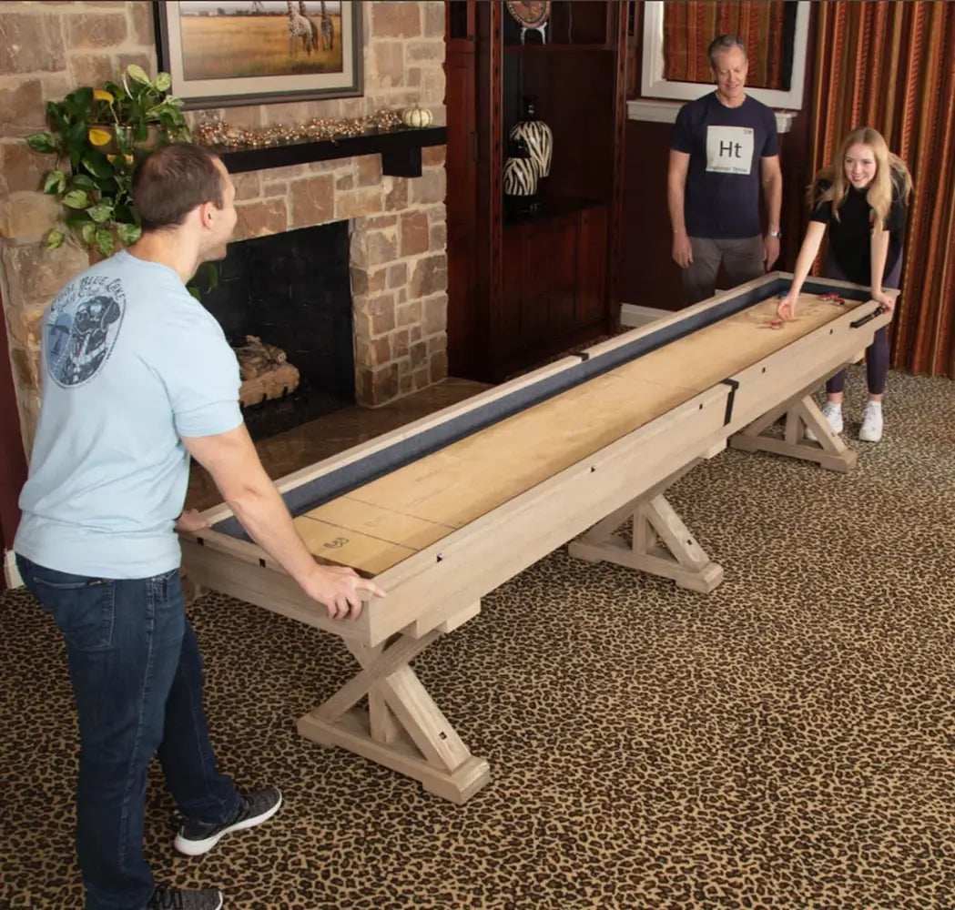 Friends playing on the Freetime Fun Rockford Rustic Oak 14ft 2-piece shuffleboard table in a home game room.