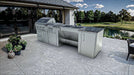 Lifestyle shot of the Sunstone Summit 10-foot ADA Outdoor Kitchen installed on a modern stone patio overlooking a lush backyard golf course and pond.
