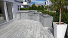 Sunstone SCPBIGTEX21 Big-Texan outdoor kitchen island installed on contemporary terrace with L-shaped counter, stainless grill, side burner, and sink.