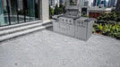 Sunstone Caprice stainless steel grill island installed on a modern stone rooftop patio with city skyline background.