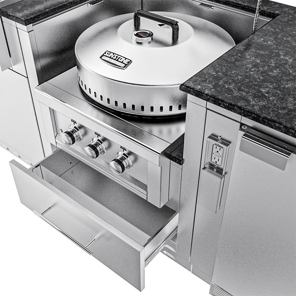 Close-up of a Sunstone Power Cirque burner with a large stainless steel cover and temperature gauge, shown next to a stone countertop with a GFCI outlet.