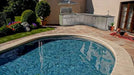 Poolside view of Sunstone Rancher L-shaped island (SCPRANCHER8.10BY11) featuring stainless gas grill, prep space, and sink station.