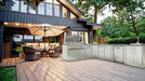Sunstone Rancher L-shaped outdoor kitchen island (SCPRANCHER8.10BY11) on a backyard deck with stainless grill, sink, and storage cabinetry.