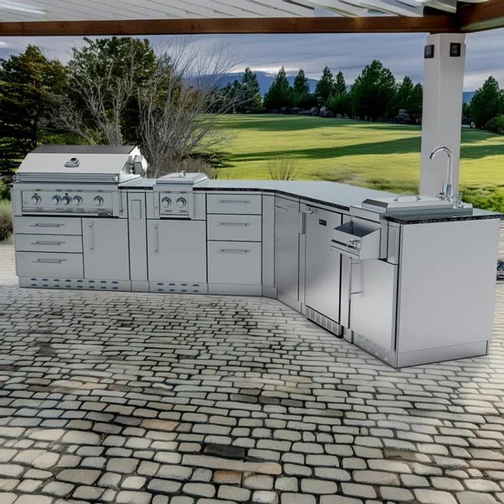 Outdoor lifestyle shot of the Sunstone Savanna 16ft stainless steel kitchen island on a cobblestone patio overlooking a lawn.