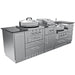 Three-quarter perspective product photograph of the complete 9-foot Sunstone TexCajun outdoor kitchen island, highlighting its deep stainless steel cabinets and integrated appliances with a dark granite countertop against a white background.