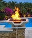 Travertine TessaRai 36 inch Square Fire/Water Bowl Kit with copper spillway, tall flames and waterfall beside tropical luxury pool