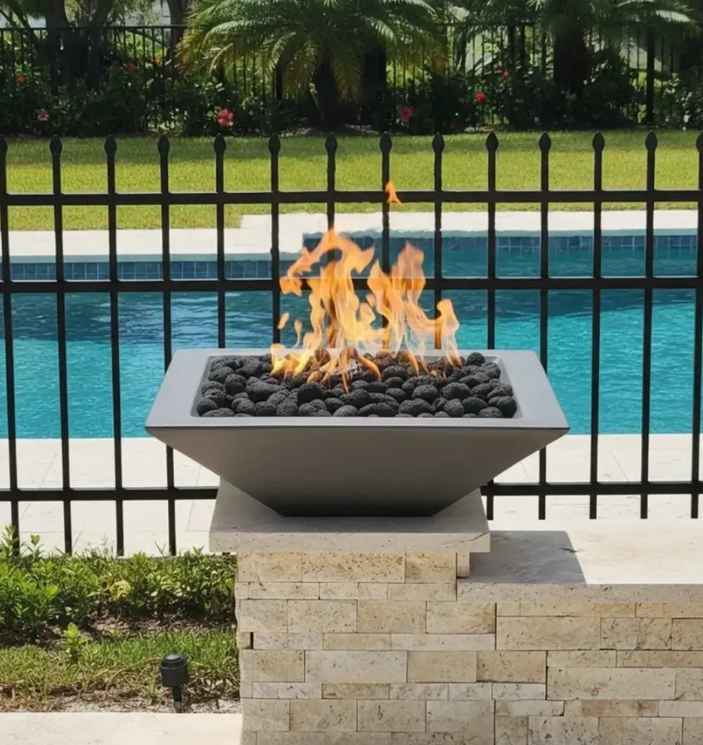 Grey Travertine TessaRai 36 inch Square Fire Bowl Kit with lava rock flames mounted on pool wall pedestal