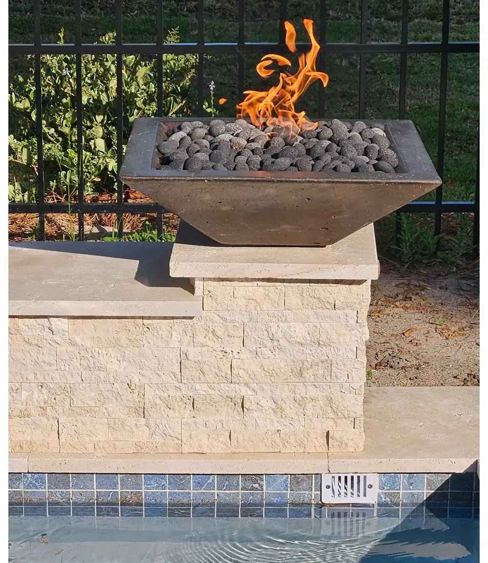 Travertine TessaRai 36 inch Square Fire Bowl Kit with lava rock on poolside stone pedestal in sunny backyard
