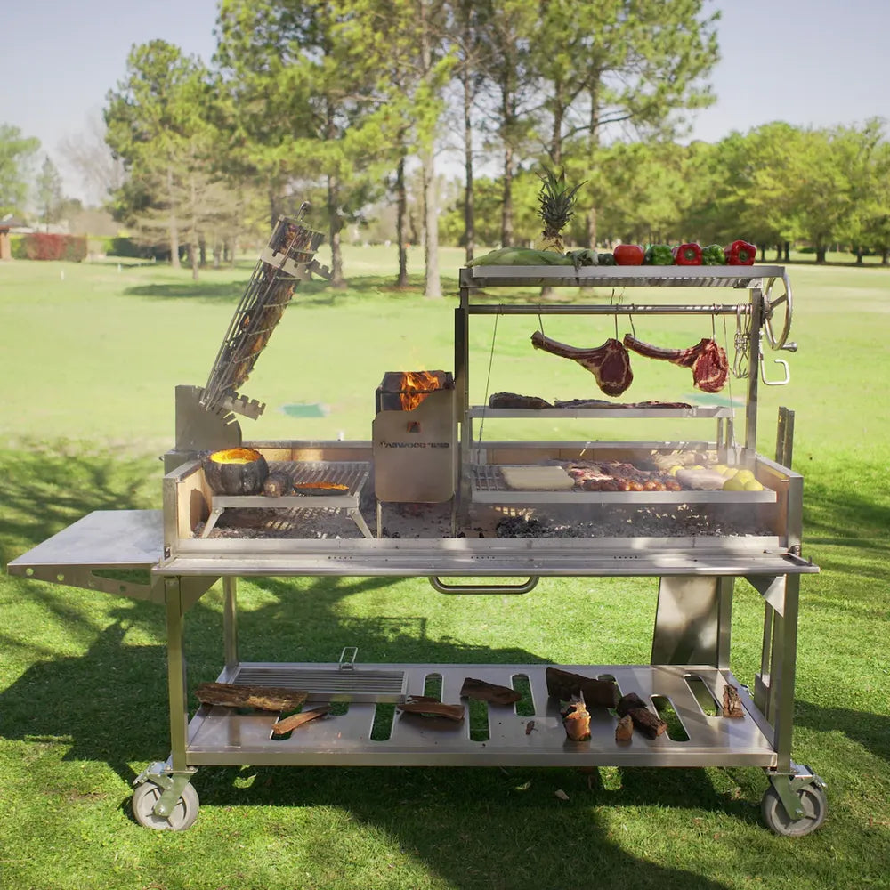 Tagwood BBQ26SS XL Santa Maria grill cooking steaks and vegetables over wood fire outdoors