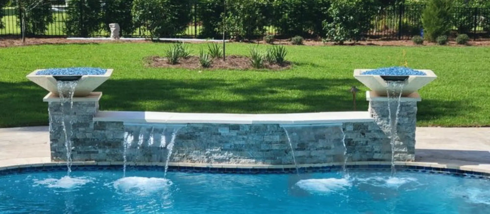 Pair of Travertine TessaRai Square Fire/Water Bowl Kits with blue fire glass and deck jets above resort-style pool