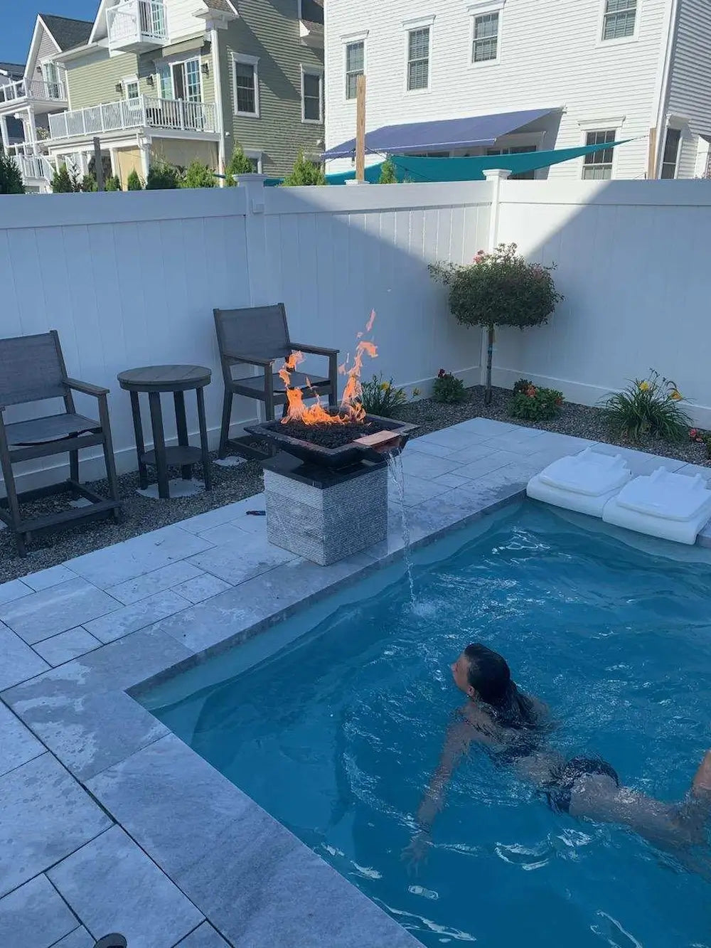 Travertine TessaRai Square Fire/Water Bowl Kit with flame and waterfall installed beside small modern plunge pool