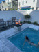 Travertine TessaRai Square Fire/Water Bowl Kit with flame and waterfall installed beside small modern plunge pool