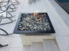 Travertine TessaRai 36 inch Square Fire Bowl Kit with black and clear fire glass on sleek raised poolside platform