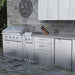 Sunstone SBC24STD 24-inch triple drawer base cabinet installed in a luxury outdoor kitchen island with a stone backsplash, integrated grill, and matching stainless steel cabinetry.