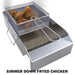 Wire fryer basket with fried chicken draining above hot oil in Sunstone stainless deep fryer insert.