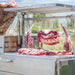 Tagwood BBQ26SS XL Santa Maria grill hanging raw beef cuts on hooks above cooking grates