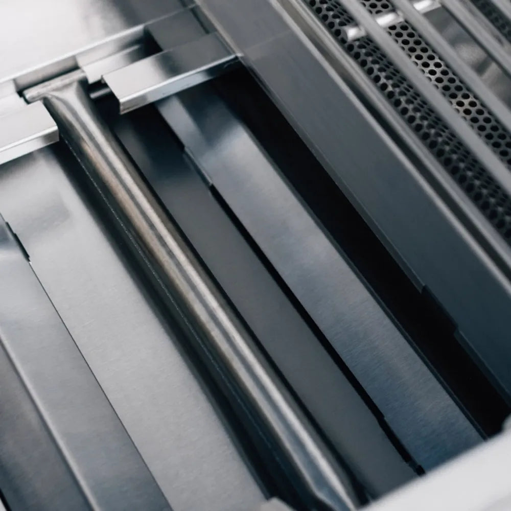 Interior view of True Flame gas grill showing heavy-duty stainless steel burners and flame tamers.