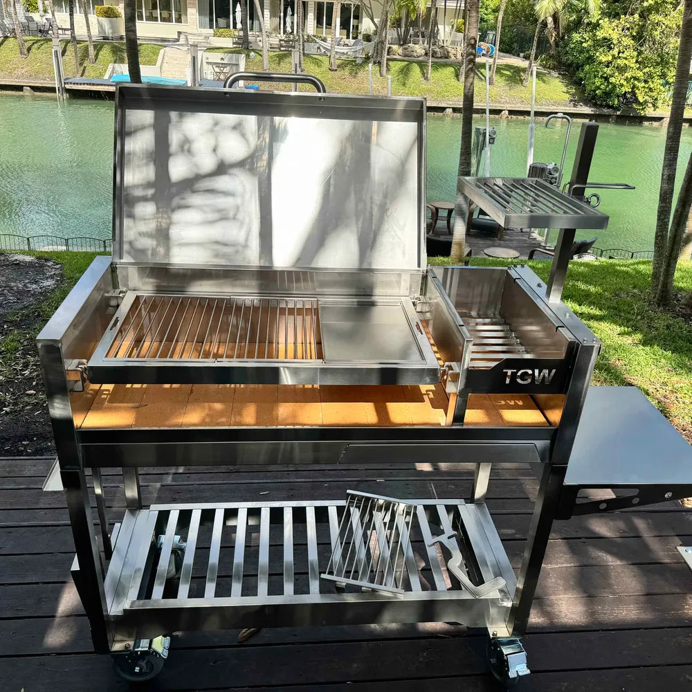 Tagwood BBQ18SS Gaucho stainless steel charcoal grill full front view with side brazier and side table outdoors