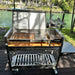 Tagwood BBQ18SS Gaucho stainless steel charcoal grill full front view with side brazier and side table outdoors