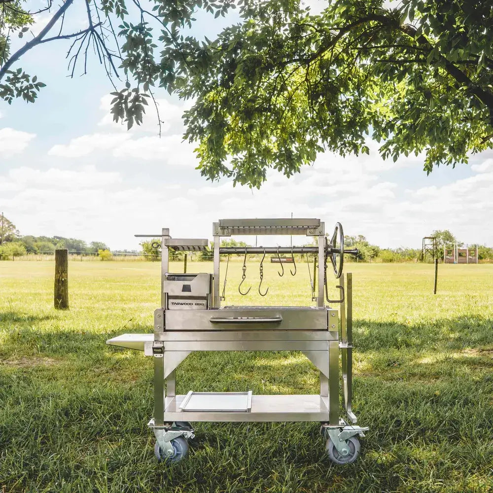 Tagwood BBQ03SS Mini Santa Maria grill front view with hanging hooks in shaded outdoor field