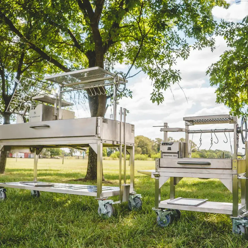 Tagwood BBQ03SS Mini Santa Maria grill next to Tagwood large Santa Maria grill in outdoor park setting