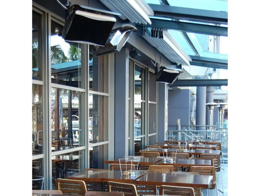 Several Bromic Platinum series heaters mounted on the ceiling of an outdoor patio, providing warmth to the seating area of a restaurant or cafe.