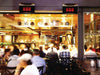 Two Bromic Platinum series heaters mounted above a busy, indoor-outdoor dining area, showing them in use to heat a crowd of people.