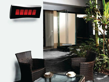 The Bromic Platinum 500 Gas Radiant Heater mounted on a white wall above a residential outdoor patio seating area, with wicker chairs and tropical plants.