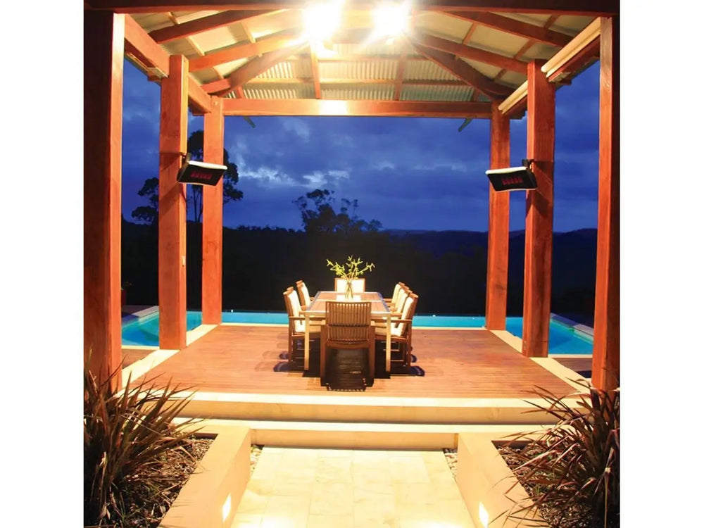 Two Bromic Platinum 500 Gas Radiant Heaters mounted on the wooden beams of an outdoor dining pavilion, overlooking a pool and a scenic, mountainous landscape at dusk.