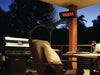 The Bromic Tungsten 300 Gas Radiant Heater mounted on a wooden post on a residential outdoor deck, providing warmth to a seating area with a table and chair.
