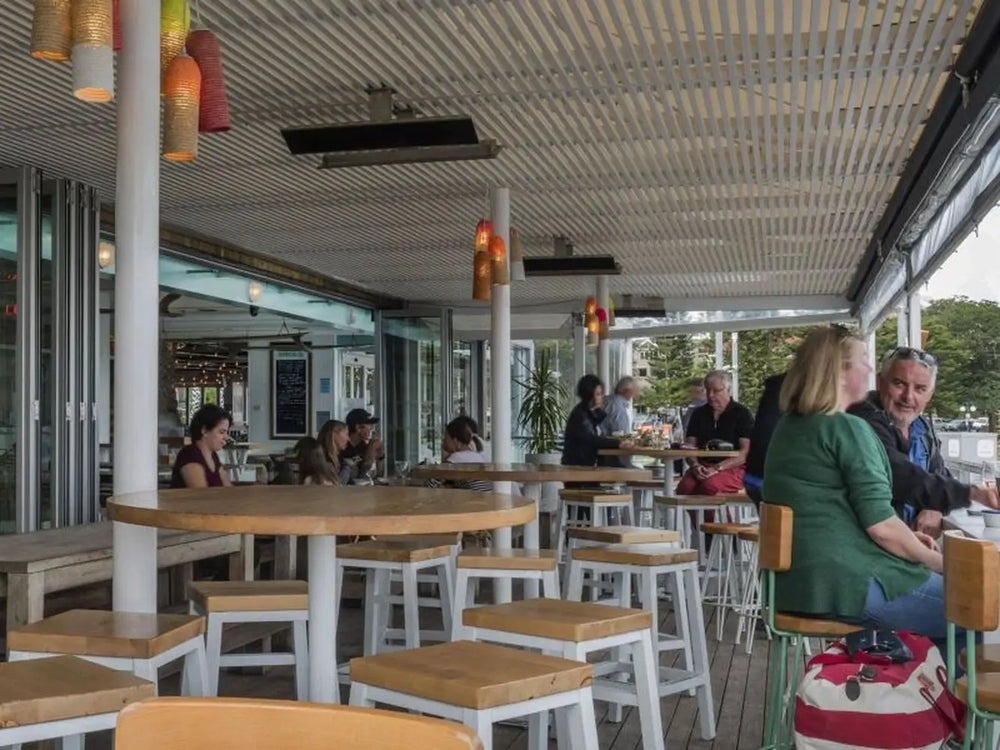 A view of an outdoor dining area with black Bromic Platinum Electric Heaters mounted on the ceiling.