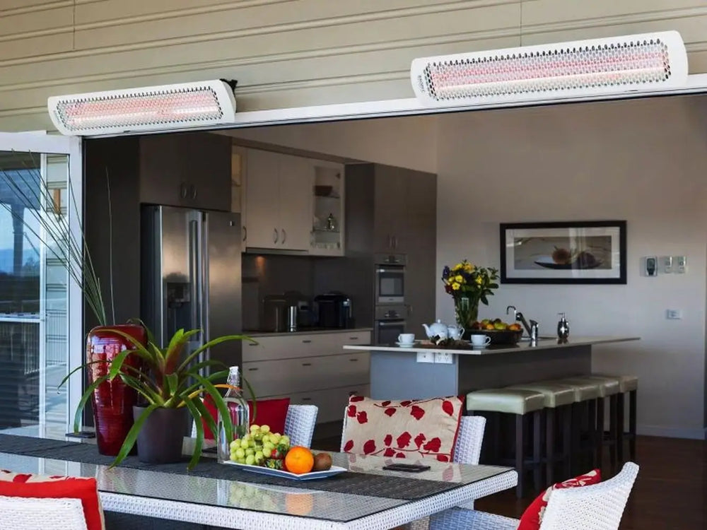Two Bromic Tungsten 6000W Electric Heaters mounted above sliding doors on a covered patio, providing radiant warmth for an indoor-outdoor kitchen and dining space.