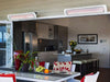 Two Bromic Tungsten 6000W Electric Heaters mounted above sliding doors on a covered patio, providing radiant warmth for an indoor-outdoor kitchen and dining space.