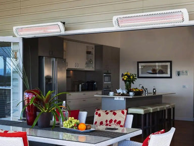 Two Bromic Tungsten 6000W Electric Heaters mounted above sliding doors on a covered patio, providing radiant warmth for an indoor-outdoor kitchen and dining space.