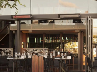 Bromic Smart-Heat black electric patio heaters mounted above modern outdoor restaurant seating area.