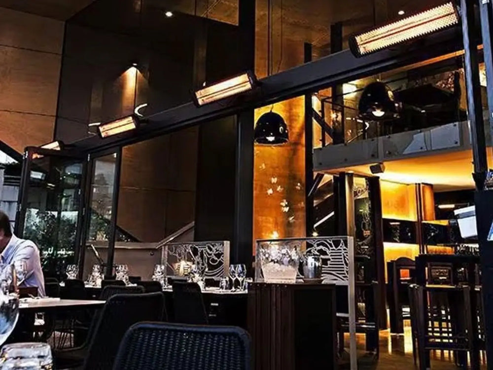 Bromic Smart-Heat black electric heaters installed on an overhead beam in a dark, upscale indoor bar.