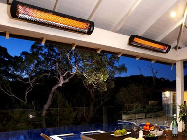 Two Bromic Smart-Heat black radiant heaters ceiling-mounted over a patio and pool deck at dusk for comfort.